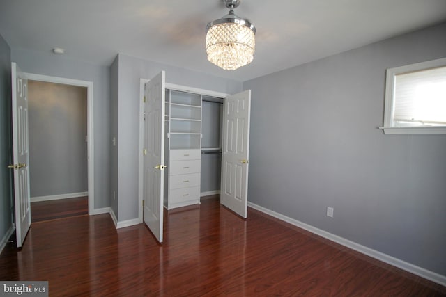 unfurnished bedroom featuring an inviting chandelier and dark wood-type flooring