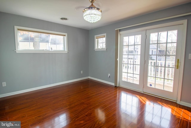 spare room featuring wood-type flooring and a chandelier