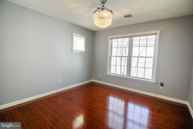 empty room with a chandelier and wood-type flooring