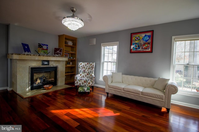 living room featuring hardwood / wood-style floors, a notable chandelier, a wealth of natural light, and a tiled fireplace