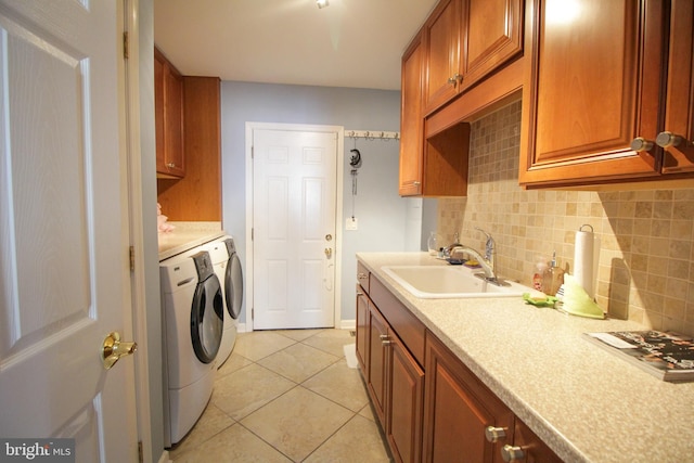 laundry area featuring light tile patterned flooring, sink, cabinets, and washing machine and clothes dryer