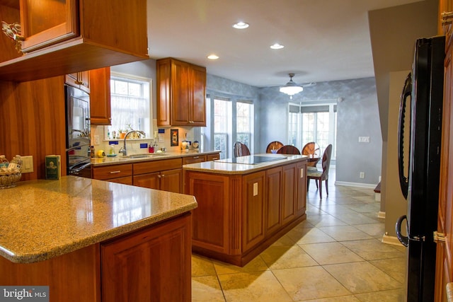 kitchen featuring sink, a kitchen island, kitchen peninsula, light tile patterned flooring, and black appliances