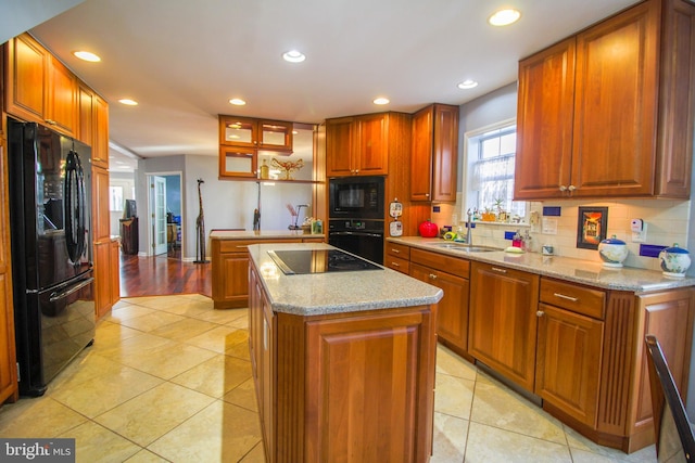 kitchen featuring a center island, backsplash, black appliances, sink, and light tile patterned floors