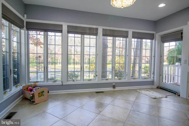 unfurnished sunroom featuring a healthy amount of sunlight and a chandelier