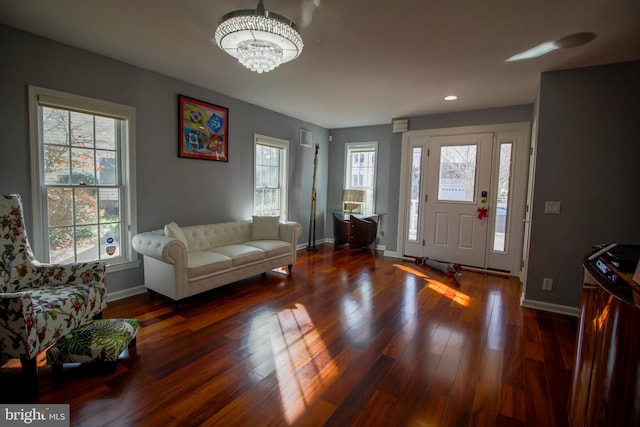 foyer featuring a notable chandelier, plenty of natural light, and dark wood-type flooring