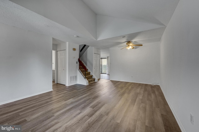 unfurnished living room with a textured ceiling, hardwood / wood-style flooring, ceiling fan, and lofted ceiling