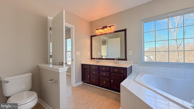 bathroom with toilet, vanity, and a relaxing tiled tub