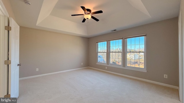 unfurnished room featuring ceiling fan, a tray ceiling, and light colored carpet