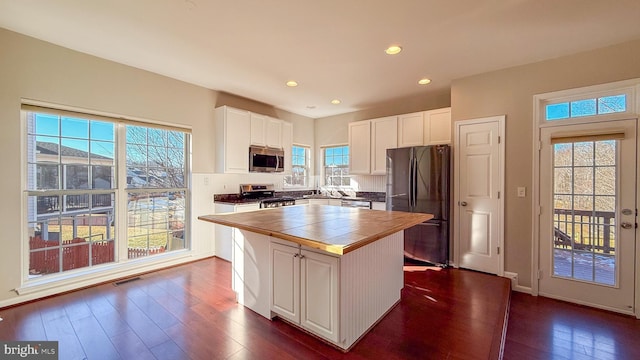 kitchen featuring appliances with stainless steel finishes, a kitchen island, white cabinets, and dark hardwood / wood-style floors