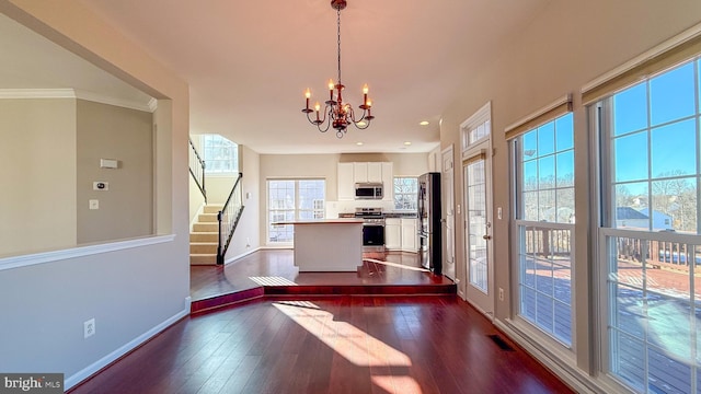 interior space with a notable chandelier, dark hardwood / wood-style floors, and ornamental molding