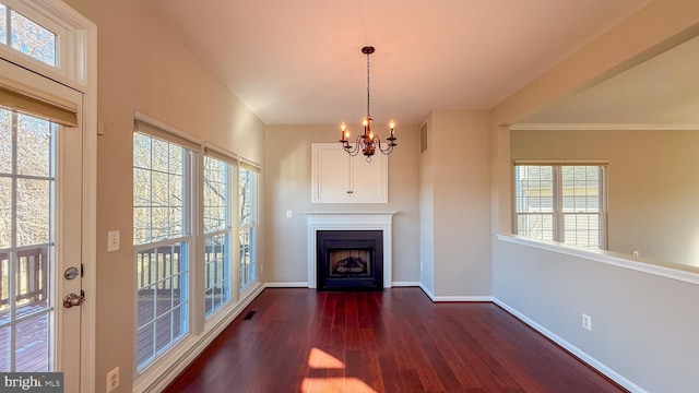 unfurnished living room featuring dark hardwood / wood-style flooring, a chandelier, and a healthy amount of sunlight