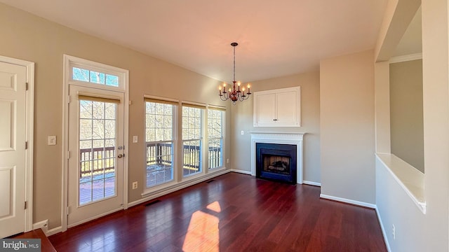 unfurnished living room with an inviting chandelier and dark hardwood / wood-style floors