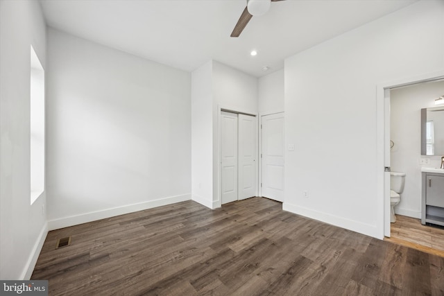 unfurnished bedroom with ensuite bath, ceiling fan, a closet, and dark hardwood / wood-style floors