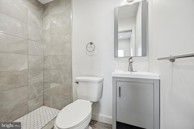 bathroom with vanity, toilet, and tiled shower