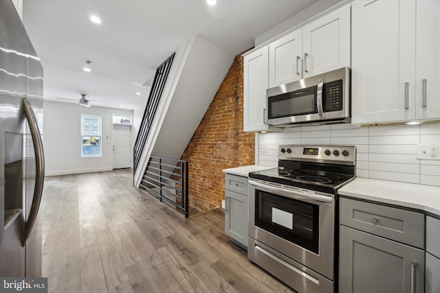 kitchen with white cabinets, gray cabinets, stainless steel appliances, and brick wall