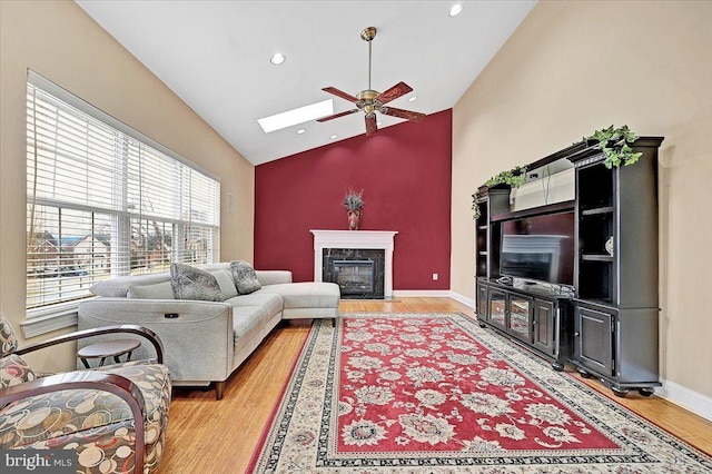 living room featuring a high end fireplace, high vaulted ceiling, light hardwood / wood-style flooring, and ceiling fan