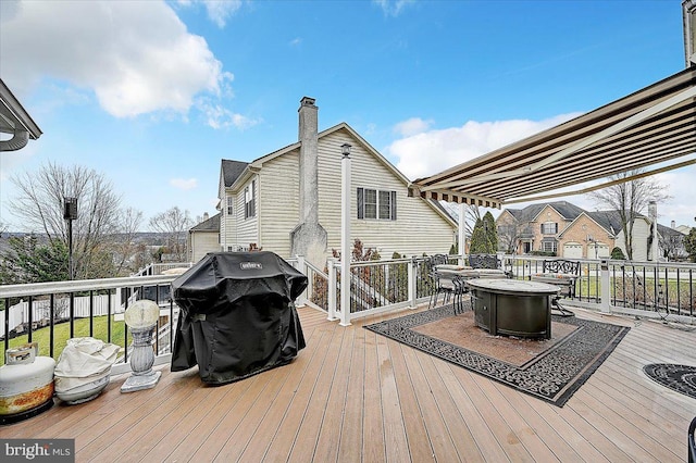 wooden terrace featuring an outdoor fire pit and a grill