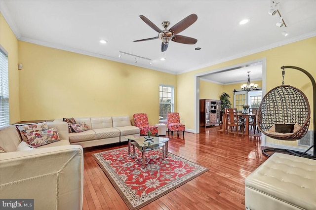 living room with crown molding, rail lighting, wood-type flooring, and ceiling fan with notable chandelier