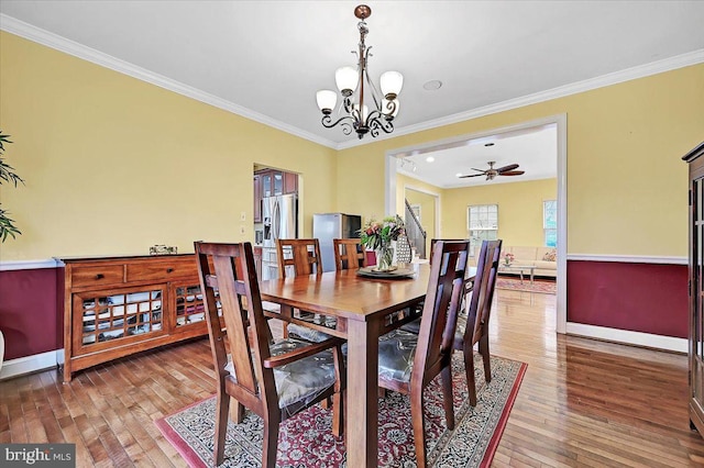 dining area featuring hardwood / wood-style flooring, ceiling fan with notable chandelier, and crown molding