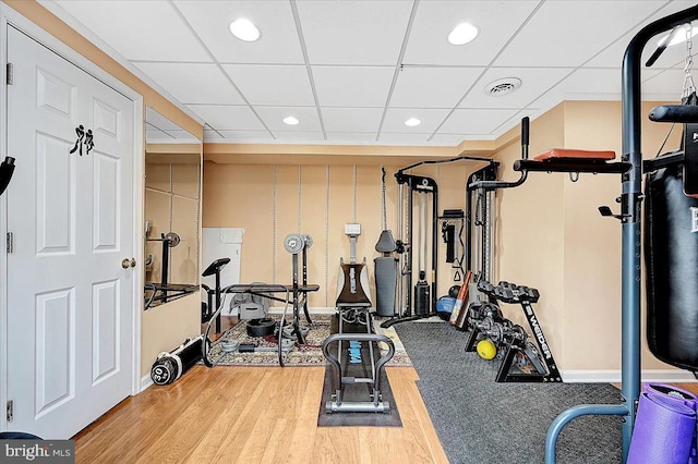 exercise area featuring hardwood / wood-style floors and a drop ceiling