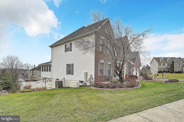 view of side of property with a yard and central AC