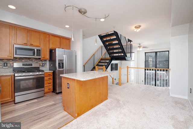 kitchen with light stone countertops, tasteful backsplash, stainless steel appliances, and light wood finished floors