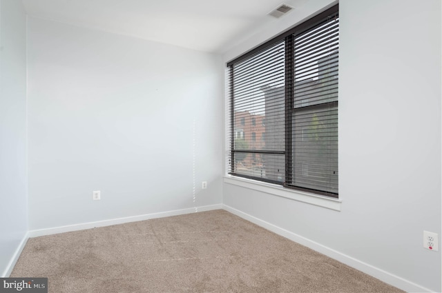 carpeted empty room featuring visible vents and baseboards