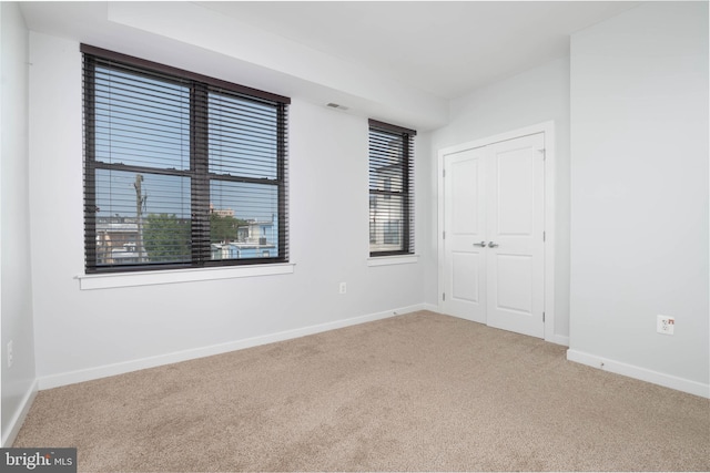 empty room with carpet, visible vents, and baseboards