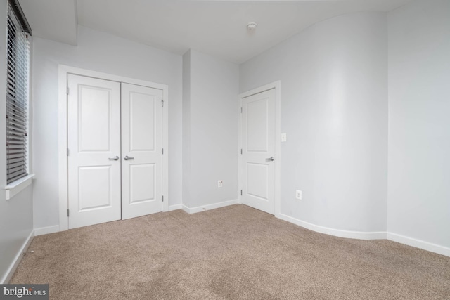 unfurnished bedroom featuring a closet, baseboards, and carpet flooring