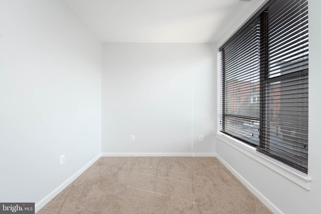 unfurnished room featuring carpet and baseboards