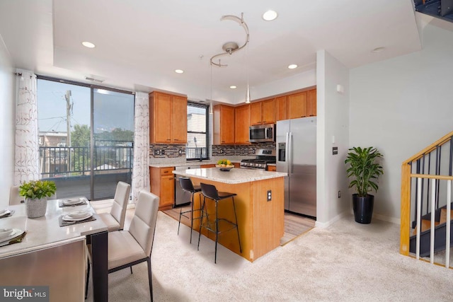 kitchen with a center island, a breakfast bar area, stainless steel appliances, light countertops, and backsplash