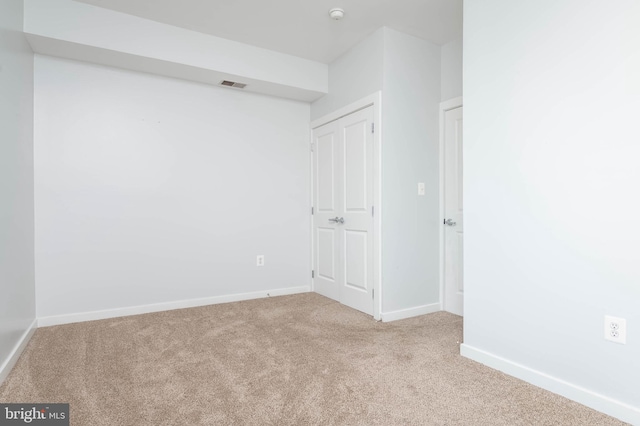 empty room with carpet, visible vents, and baseboards