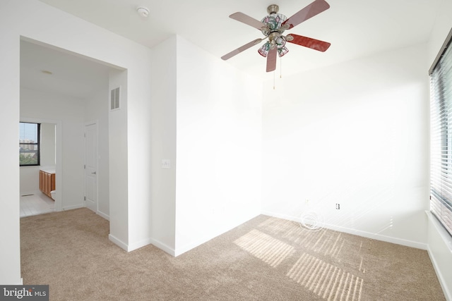 carpeted empty room with a ceiling fan, visible vents, and baseboards