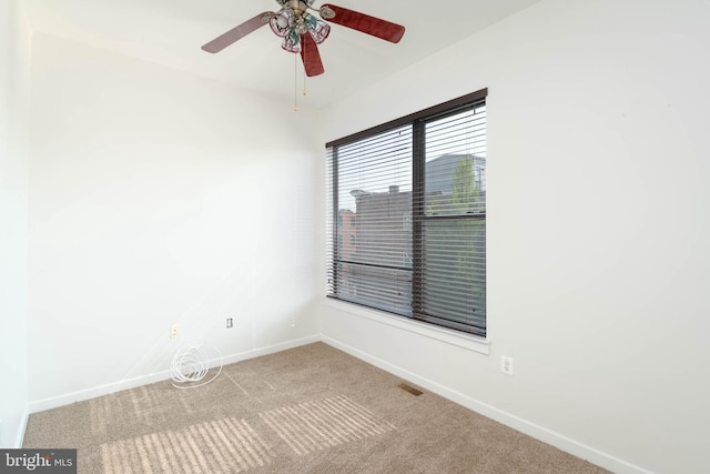 empty room featuring carpet, a ceiling fan, and baseboards