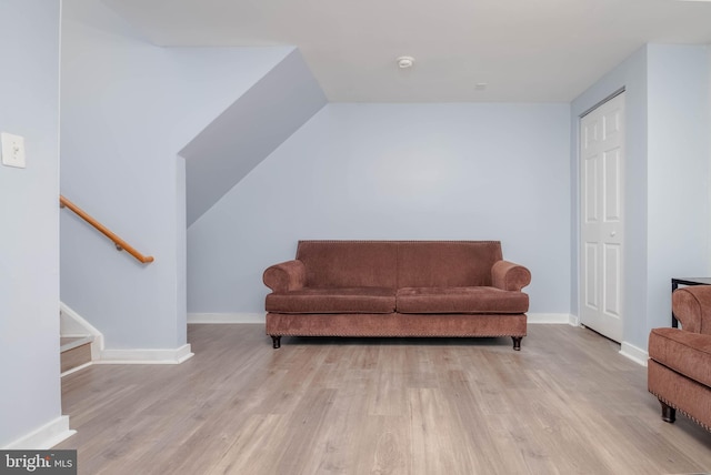 living area featuring stairs, vaulted ceiling, wood finished floors, and baseboards