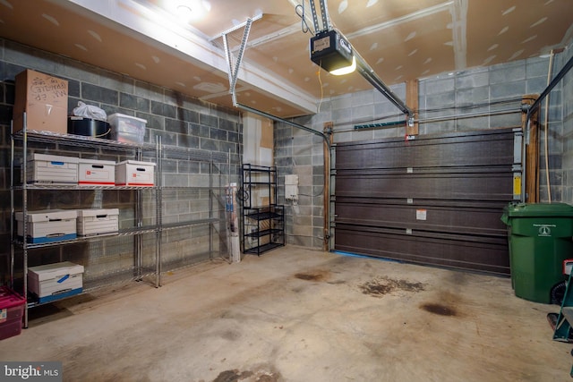 garage featuring concrete block wall and a garage door opener