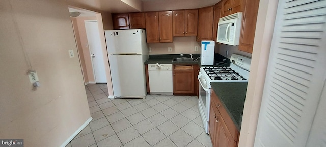 kitchen with light tile patterned floors, white appliances, and sink