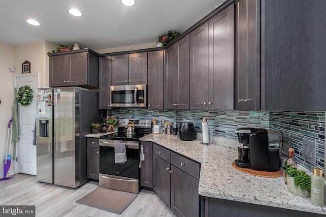 kitchen featuring light stone countertops, tasteful backsplash, dark brown cabinets, stainless steel appliances, and light hardwood / wood-style floors