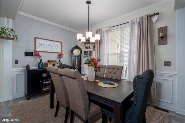 dining area featuring an inviting chandelier, crown molding, and light hardwood / wood-style flooring