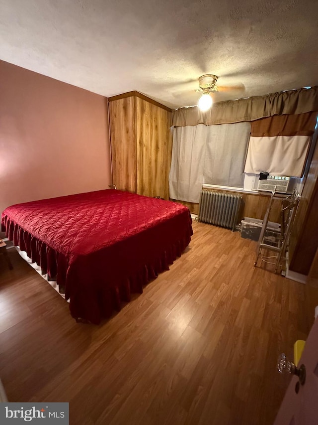 bedroom featuring radiator heating unit, a textured ceiling, ceiling fan, and hardwood / wood-style floors