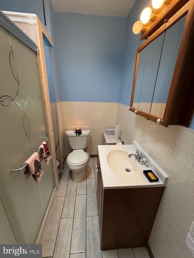 bathroom with vanity, toilet, and tile walls