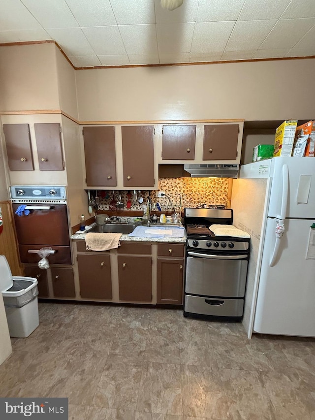 kitchen featuring ventilation hood, oven, white refrigerator, sink, and stainless steel range oven