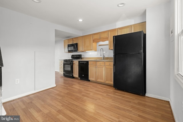 kitchen featuring sink, light brown cabinetry, black appliances, and light wood-type flooring