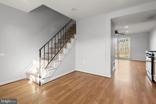 stairs with wood-type flooring and ceiling fan