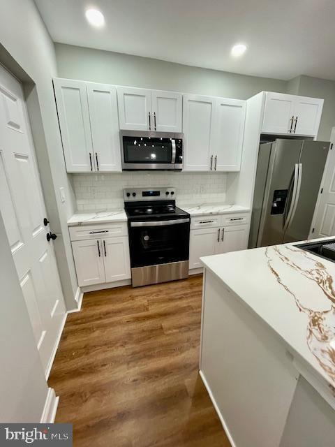 kitchen featuring white cabinets, decorative backsplash, dark hardwood / wood-style floors, and stainless steel appliances