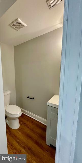 bathroom with toilet, vanity, and hardwood / wood-style flooring