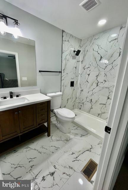 bathroom featuring a tile shower, vanity, and toilet