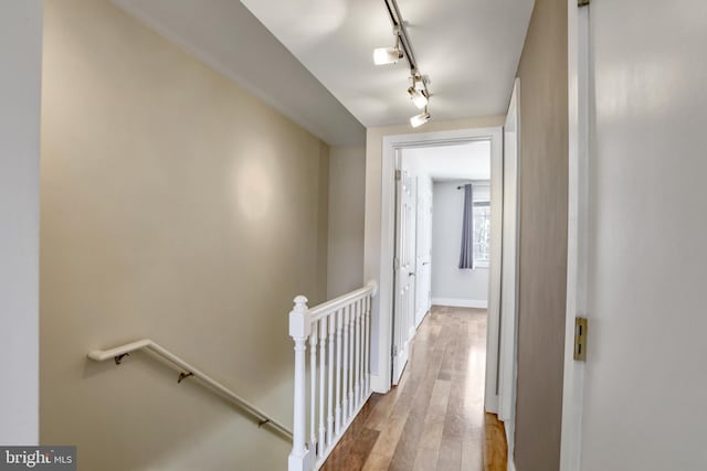 corridor with wood-type flooring and rail lighting