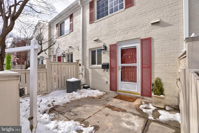 snow covered property entrance featuring a patio area