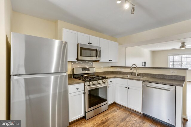 kitchen with white cabinets, ceiling fan, sink, and stainless steel appliances